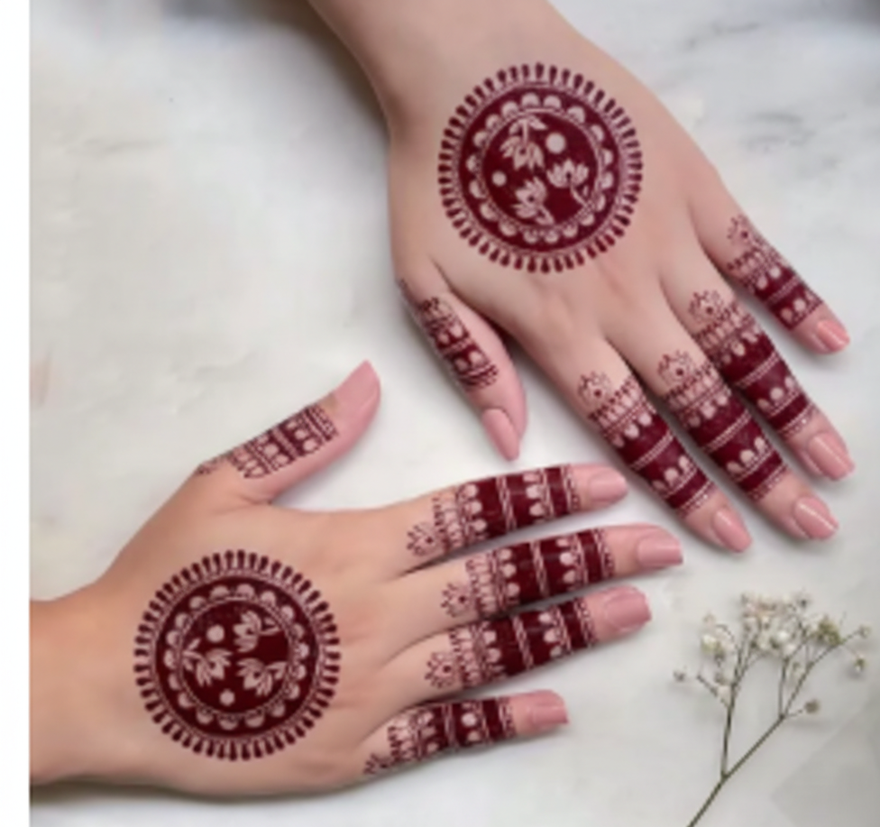 Hands with intricate red henna designs on a light background